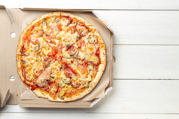 Pizza in a cardboard box against a white background. Space for text. View from above. Pizza delivery.