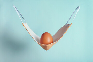 Brown chicken egg with pink fabric medical mask as a hammock