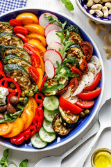 Healthy salad with vegetables, feta cheese and herbs on a plate, close-up.  An idea for nutritious and healthy eating.