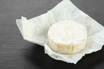 Camembert cheese circle on a black background.