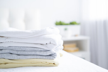 stack of women colorful sweatshirts, hoodies in pastel colors on white bed. Seasonal shopping, laundry, vacation concept