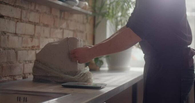 Ceramist cuts a piece of clay to make pottery at the workshop, potter at work, craftsmanship of making goods from clay, 4k 60p Prores HQ 10 bit