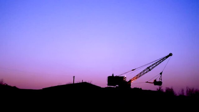 The excavator is digging at sunset. The tractor is digging a hole. The escalator is digging with a bucket.