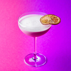 Closeup glass of milk liquor based cocktail on a purple background