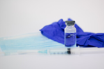 Vial vaccine, glass ampoules and a syringe with medical protective mask on white background, global...