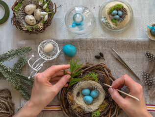A nest with three white Easter eggs and bunny ears at home on Easter day. Celebrating Easter at spring. Painting eggs.