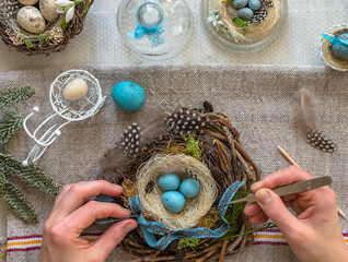 A nest with three white Easter eggs and bunny ears at home on Easter day. Celebrating Easter at spring. Painting eggs.