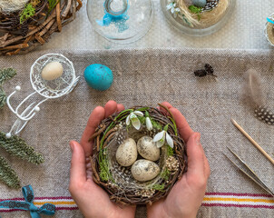 A nest with three white Easter eggs and bunny ears at home on Easter day. Celebrating Easter at spring. Painting eggs.