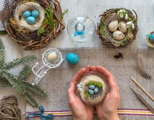 A nest with three white Easter eggs and bunny ears at home on Easter day. Celebrating Easter at spring. Painting eggs.