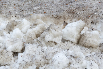 Early spring time dirty gray melted snow with sand pattern texture close-up