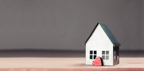 Layout of a paper house. On a wooden table. The concept of construction, rent, purchase, loan, home protection. Red heart.