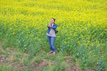 A woman takes a selfie at the edge of a rapeseed field. Russia