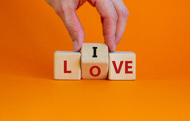 Live your love symbol. Businessman turns cubes and changes the word 'live' to 'love'. Beautiful orange background, copy space. Business, live your love concept.
