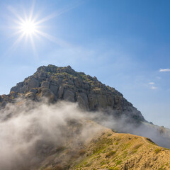 mount top in dense clouds under a sparkle sun