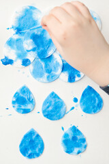 Obraz na płótnie Canvas Let's make the rain. Boy coloring drop shape cotton pads. 5 minute crafts for children activities. Creative solutions at home.