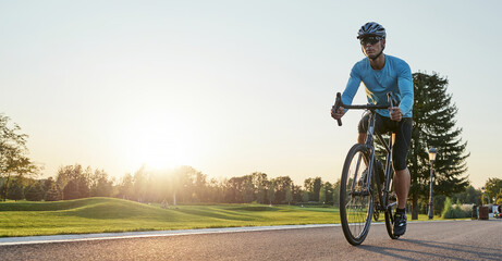 Website header of Rear view of athletic man in sportswear standing with bicycle on the road. Riding mountain road bike on a sunny summer day