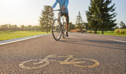 Close up of a bicycle sign drawn on asphalt. Professional male cyclist riding a road bike on a cycle path in the background