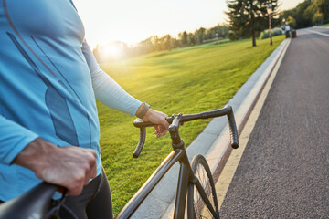 Close up of professional male cyclist in sportswear standing with his bike on a cycle path in the morning
