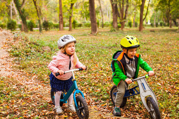 Cheerful preschool kids outdoors on balance bikes