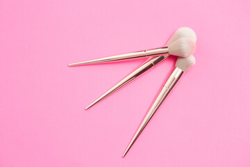 top view of make-up brushes of different sizes on a pink background