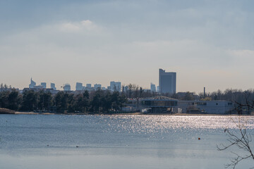 Gennevilliers, France - 02 27 2021: Chanteraines park. Nature in bloom in spring season. View of the artificial pond and the towers of La Defense district behind