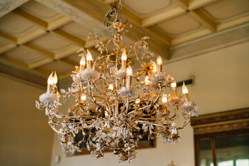 Crystal chandelier with candles in a floral style in the interior of a villa in italy.