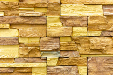 The wall of the house is made of yellow stone.