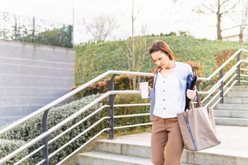 Young adult woman smiling beautiful businesswoman leaving working with coffee to go laptop and folder. successful business woman concept.copy space