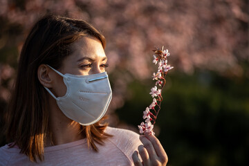 Girl with protective mask holding blooming branch