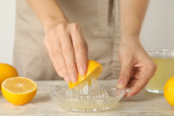 Woman juicing lemon at white wooden table, closeup