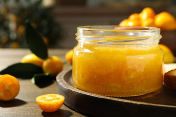 Delicious kumquat jam in jar on wooden table, closeup