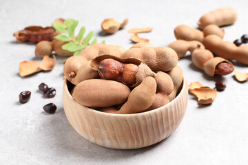 Delicious ripe tamarinds in wooden bowl on light table