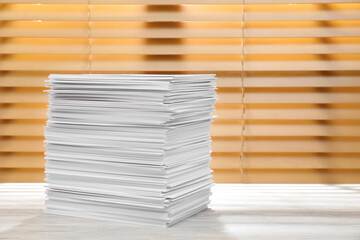 Stack of paper sheets on white wooden table. Space for text