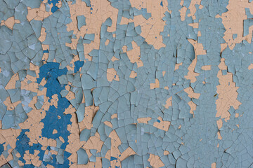 Peeling paint on the wall. Old concrete wall with cracked flaking paint. Weathered rough painted surface with patterns of cracks and peeling. High resolution texture for background and design. Closeup