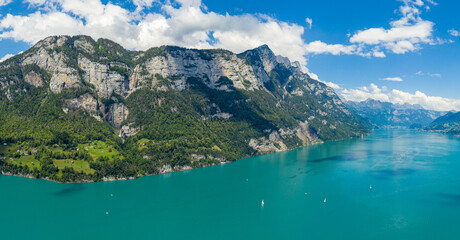 Aerial drone shot over beautiful Walensee  lake, Switzerland, with the view to Seerenbach waterfalls and boats and yacht sailing through turquoise waters of lake
