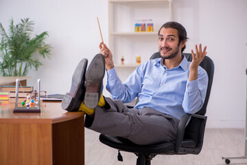Young male teacher physicist in the classroom
