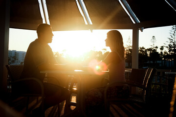 happy couple at a table by the sea at sunset nature