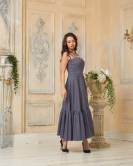 Young beautiful tall slim caucasian brunette woman in elegant dress posing in bright interior