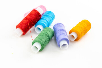 assorted reels of multi-colored thread red, blue and orange on an isolated background