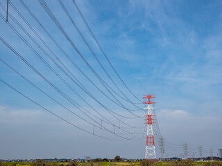 昼間障害標識の紅白塗装がされた送電鉄塔と送電線