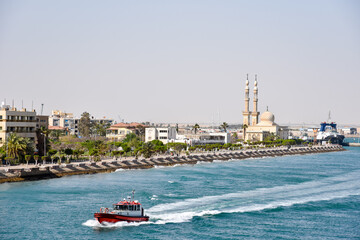 Suez Canal, pilot boat sailing near Suez city. View from transiting cargo ship.