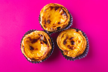Top view of typical Portuguese dessert pastry Pastéis de Nata - Portuguese egg custard tart, with a magenta background 