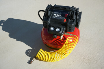 Portable electric air compressor with coiled hose.