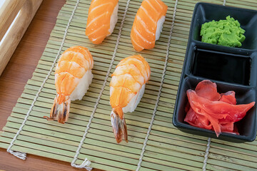 set of fresh sushi salmon and shrimps, ginger and wasabi on a background of bamboo mat