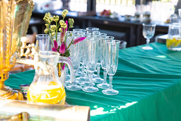 transparent glass goblets next to a carafe of orange juice summer holiday