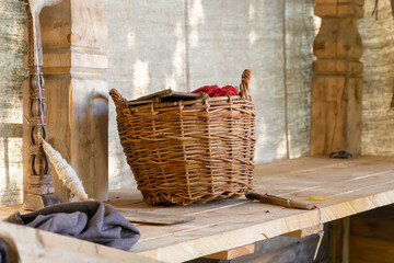 traditional wicker basket of willow stands old on the work table of needlewomen