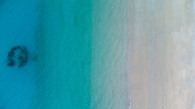 美しいケラマブルーの海と砂浜に白波が立つドローン俯瞰写真