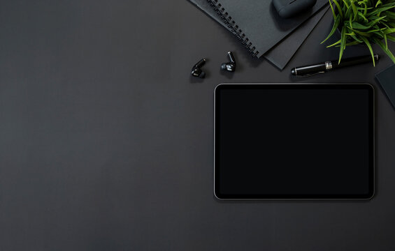 Top view creative workspace with tablet and gadget on black background, copy space.