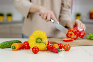 Woman cuts ripe vegetables in the kitchen.