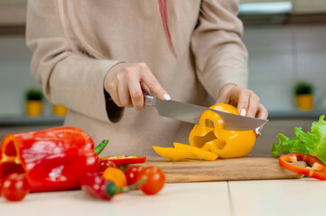 Woman cuts ripe vegetables in the kitchen.